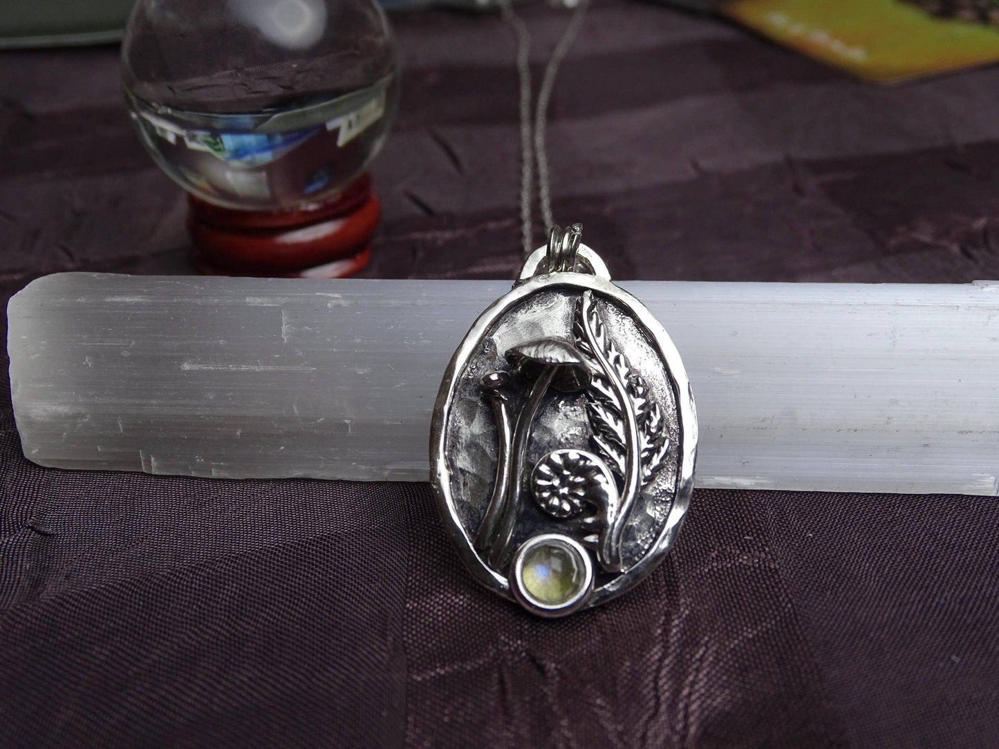 Nature-themed sterling silver pendant with mushroom, fern, and labradorite, symbolizing new beginnings, shown in a centered product display.