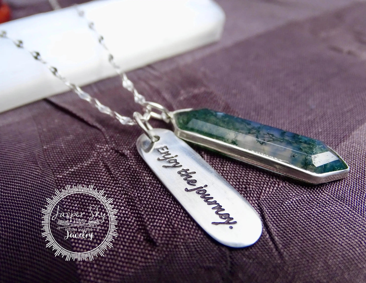 Close-up of sterling silver moss agate pendant with 'Enjoy the Journey' charm, showcasing elegant craftsmanship and natural stone detail.