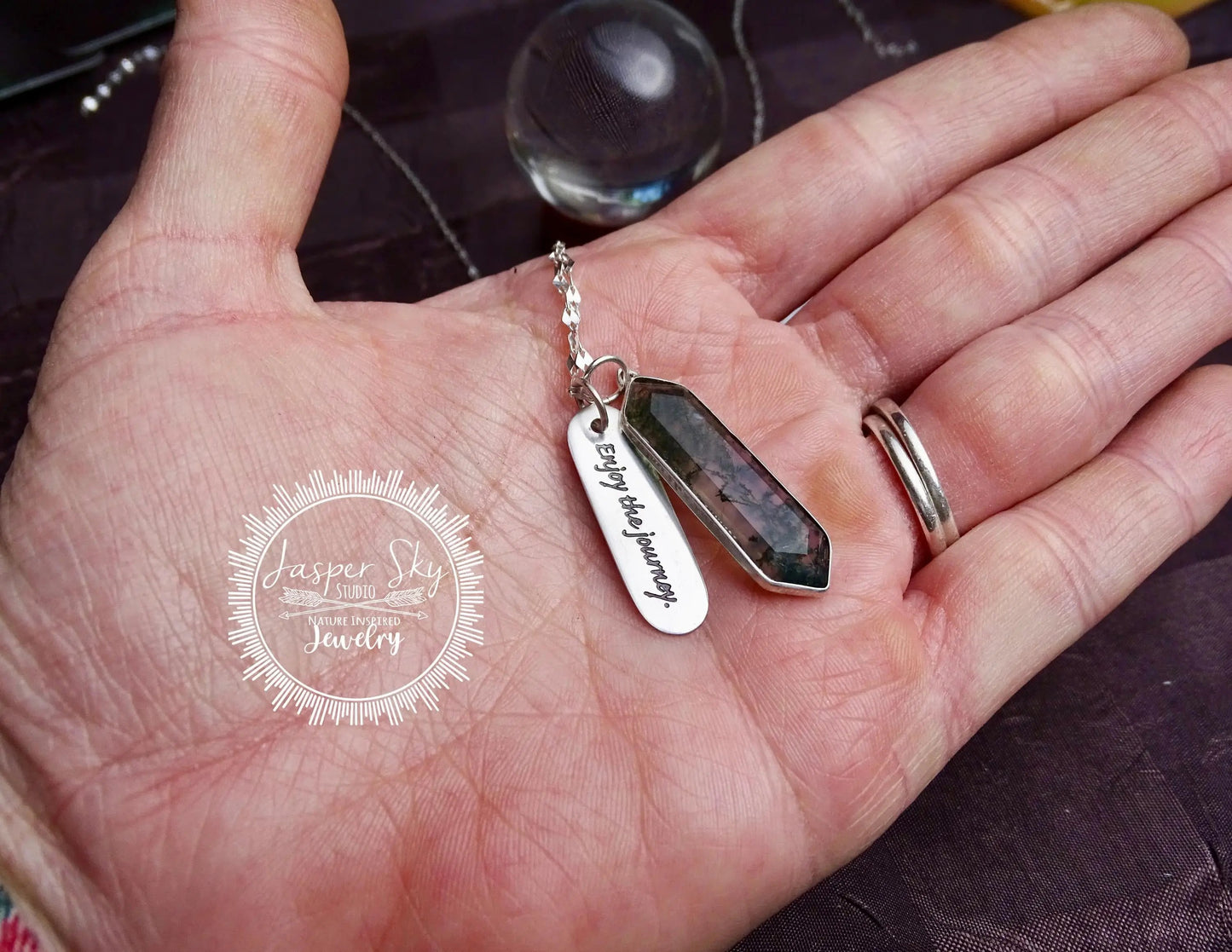 Sterling silver moss agate pendant necklace shown in hand for scale, featuring engraved inspirational charm and hexagon gemstone.