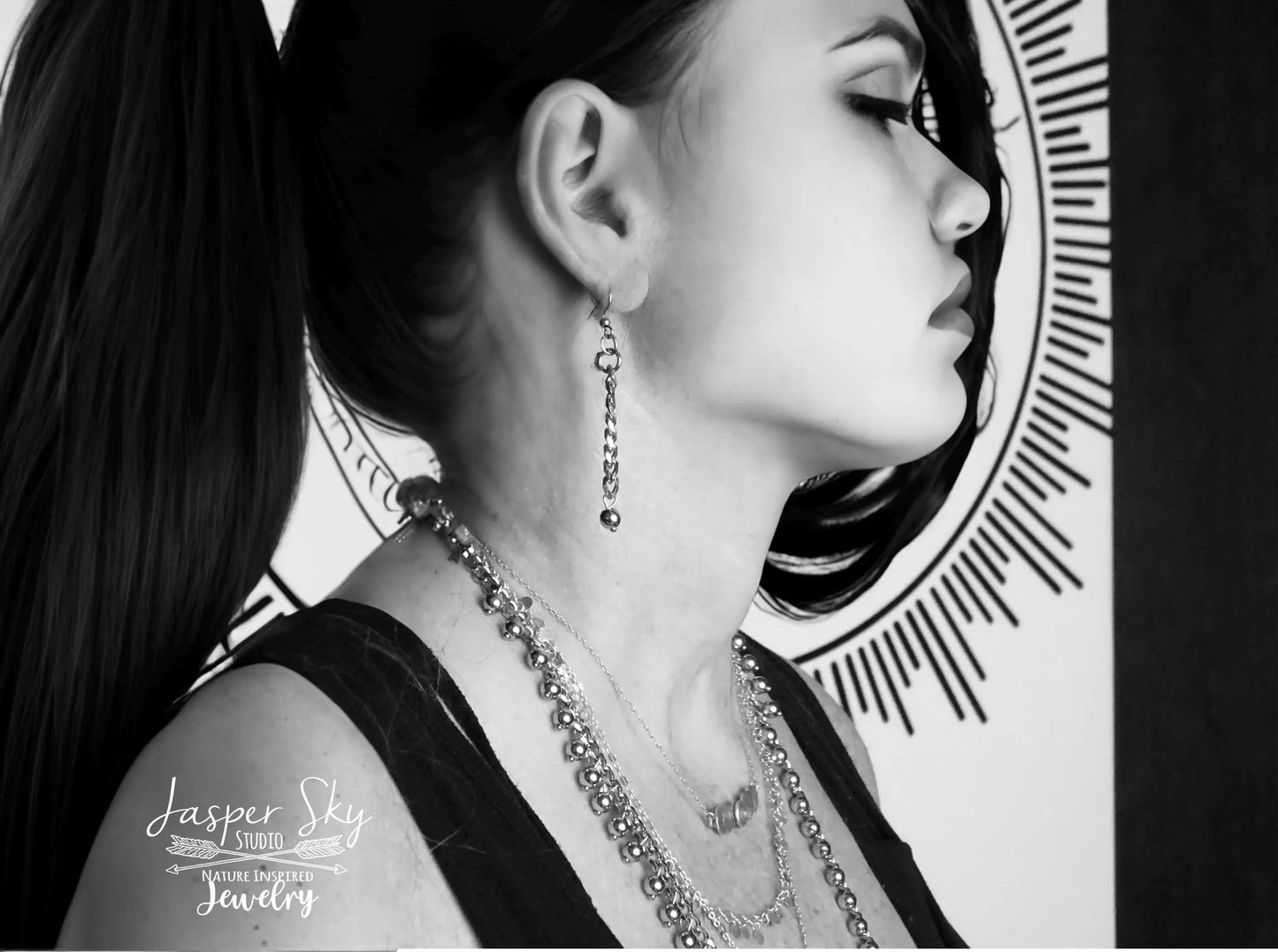 Model wearing layered gold dangle jewelry including earrings and necklaces. Boho chic fashion accessories.