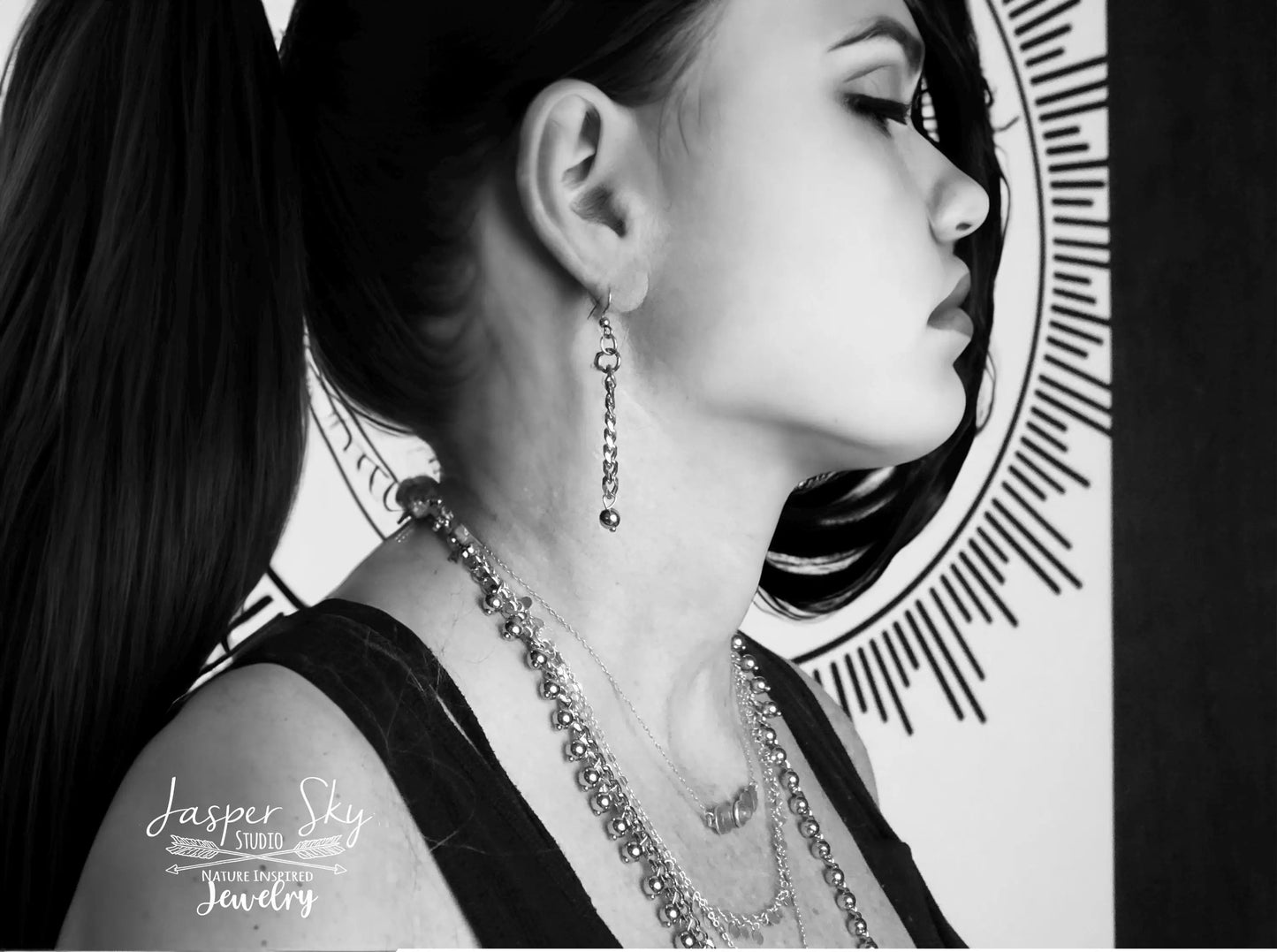 Side profile of woman wearing layered silver dangle jewelry including earrings and necklaces, showcasing boho chic elegance.